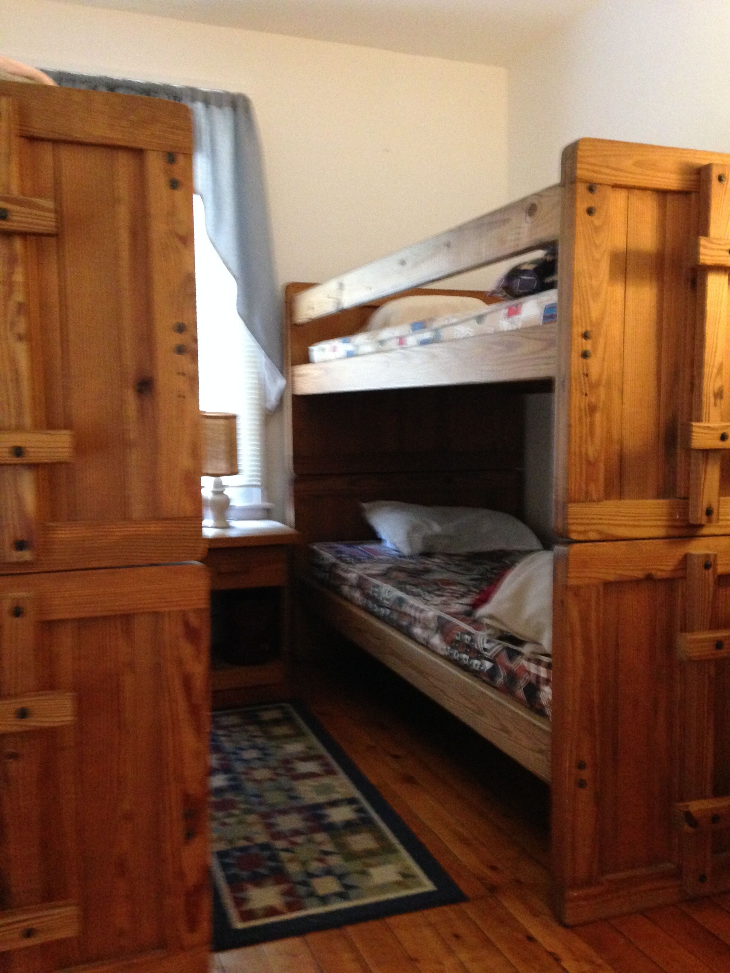 A bunk bed room with wooden furniture and a patterned rug.