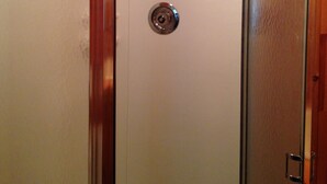 Een kamer met houten lambrisering, een witte deur en een metalen handgreep.