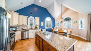 A spacious kitchen with wooden cabinets, a granite island, and a dining area with a table and chairs.