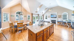 A spacious kitchen with a large island, wooden cabinets, and a dining area with a table and chairs.