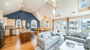 A spacious living area with a kitchen, dining area, and a large window offering a view of the city.