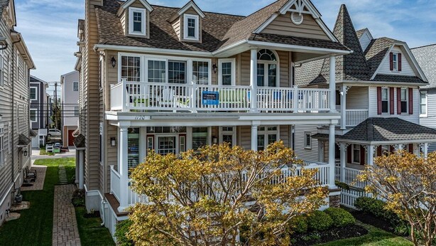 A two-story house with a balcony, a front porch, and a well-maintained lawn.