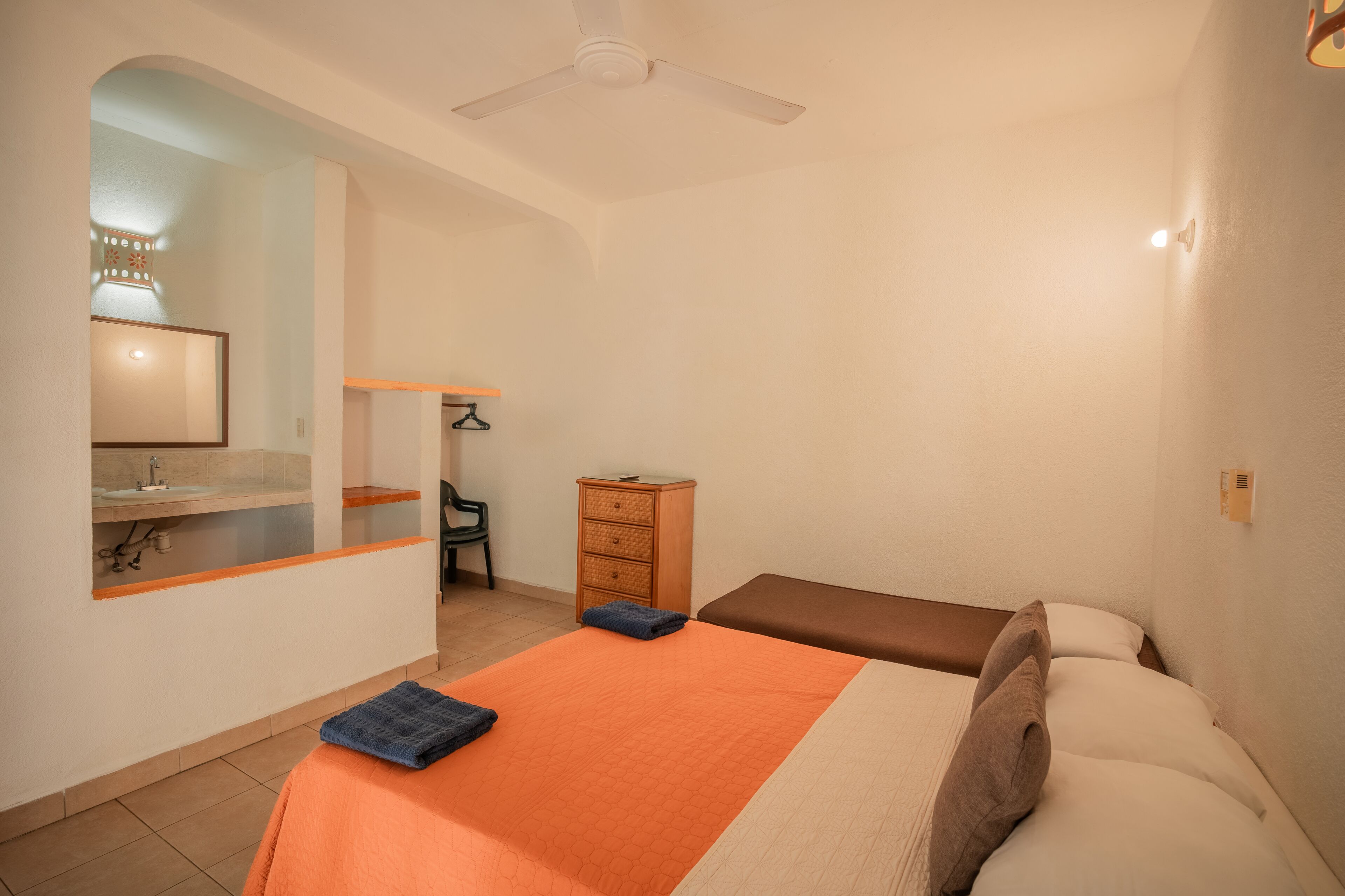 A bedroom with a bed, a nightstand, a dresser, a chair, and a ceiling fan.