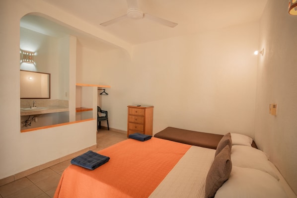A bedroom with a bed, a nightstand, a dresser, a chair, and a ceiling fan.