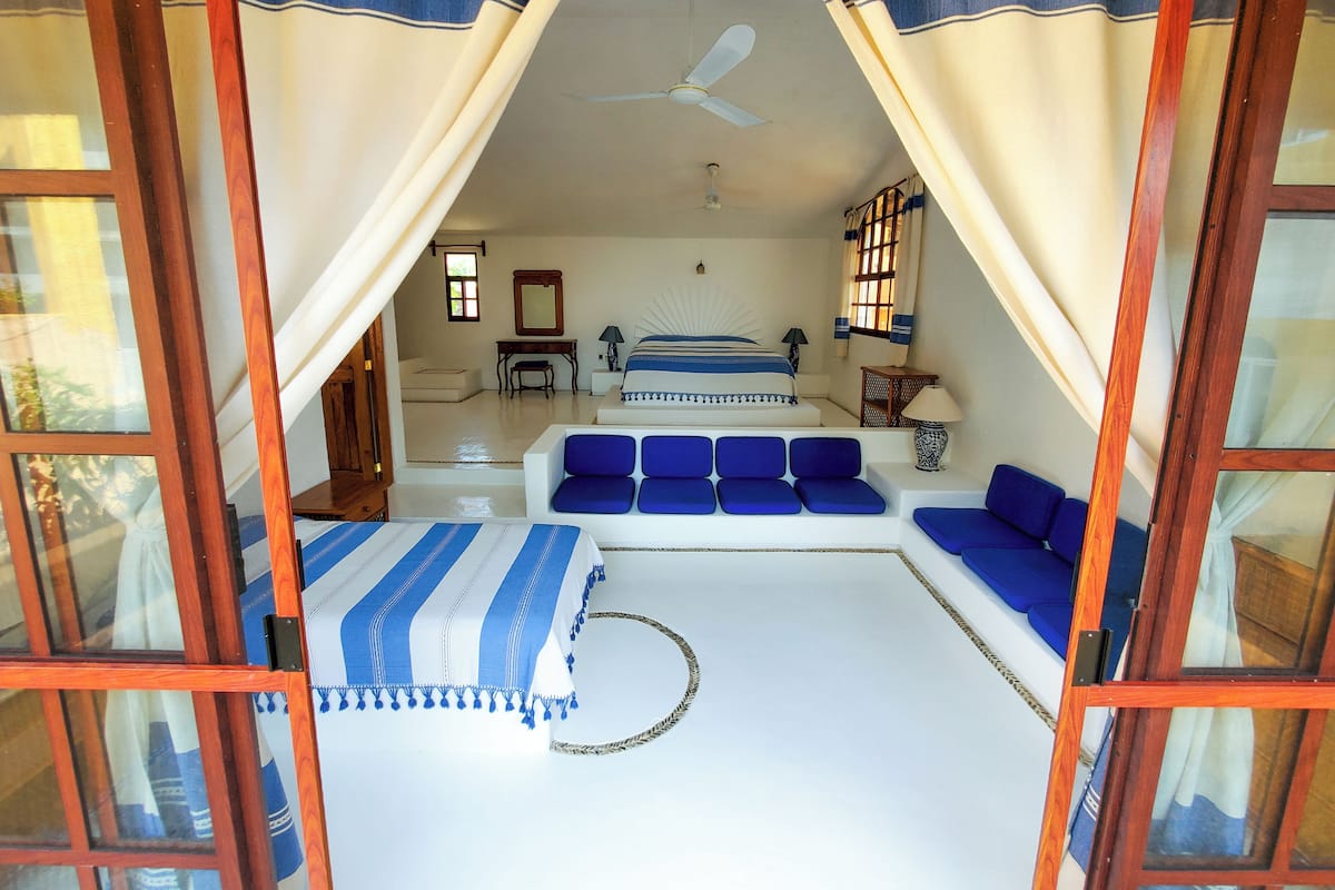 A bedroom with a bed, blue sofa, and a small table with a lamp.