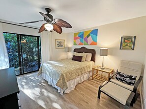 A bedroom with a bed, a chair, a desk, a ceiling fan, and artwork on the walls. - STEPS FROM PRIVATE GATED BEACH, RENOVATED 4 BEDRM w/ 2 BALCONIES & 2 PATIOS (Miramar Beach)