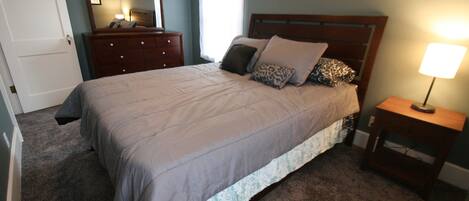 Un dormitorio con cama, cómoda, espejo y lámpara de noche.