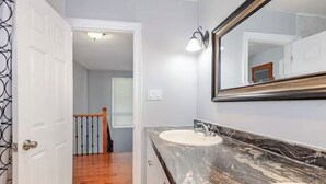 A bathroom with a marble countertop, a white sink, and a large mirror. - Falls Holiday House Niagara Falls (Niagara Falls)