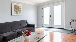A living room with a dark leather sofa, a glass coffee table with a vase of flowers, and a framed picture on the wall. - Falls Holiday House Niagara Falls (Niagara Falls)