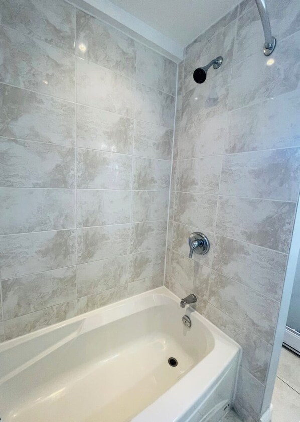 A bathroom with a freestanding bathtub, tiled walls, and a showerhead.