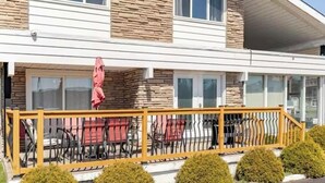 A two-story building with a stone facade, a covered patio with outdoor seating, and a wooden railing. - Falls Holiday House Niagara Falls (Niagara Falls)