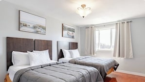 A hotel room with two beds, a large window with curtains, and artwork on the walls. - Falls Holiday House Niagara Falls (Niagara Falls)