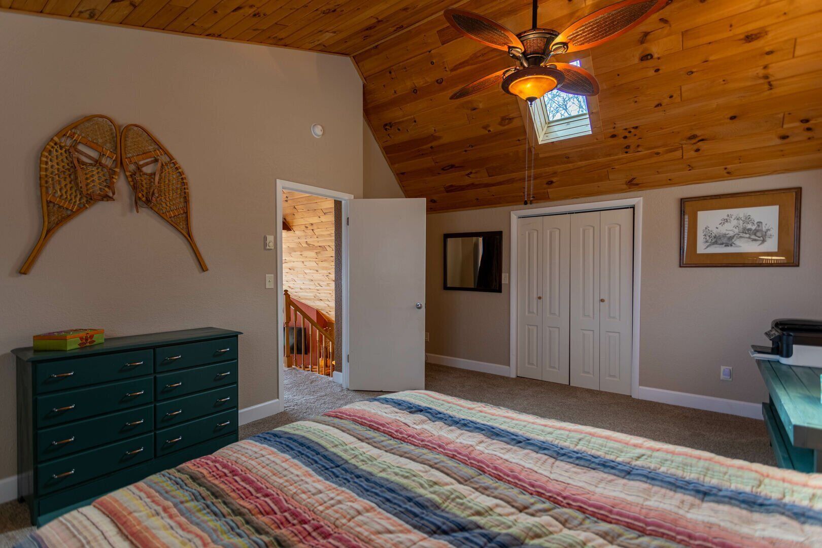 Vaulted knotty-pine ceiling and a skylight overhead, vintage snowshoe wall decor adding a touch of mountain charm.