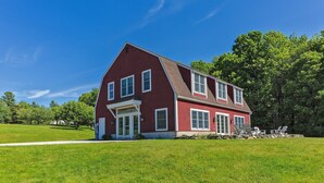 A two-story red house with a front porch and a stone foundation. - Spectacular Views and Sunsets in the Lake Sunapee Region (New London)