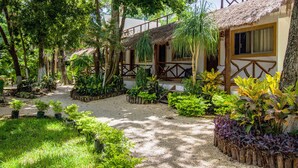 A garden with a pathway leading to a building with a thatched roof and wooden railings.