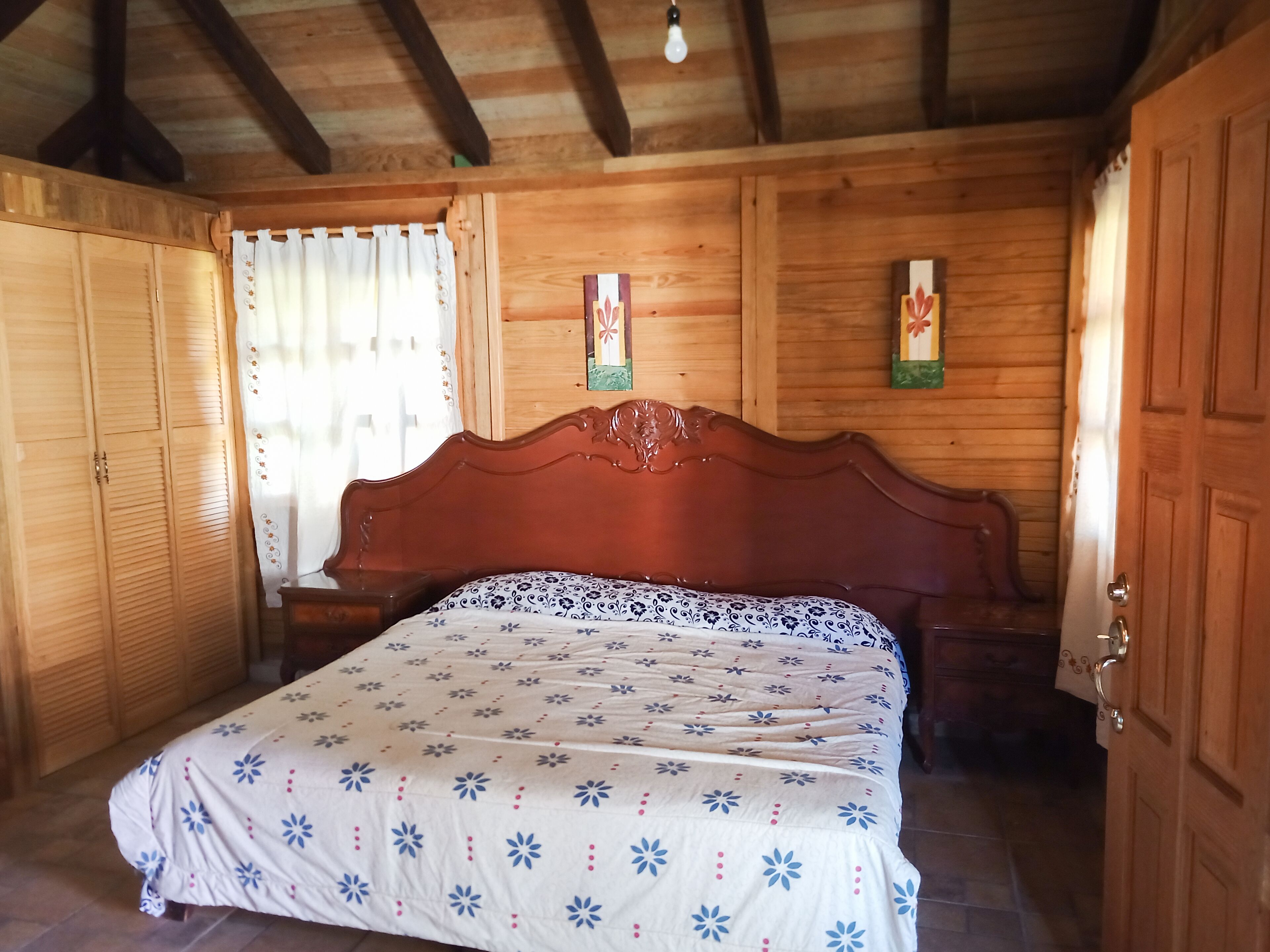 A wooden bedroom with a bed, a wardrobe, and a nightstand.