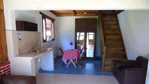 A compact living space with a kitchenette, dining area, and a staircase. - Calkiní Cabañas (San Cristóbal de las Casas)