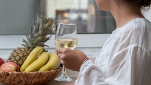 A person sitting by a window with a bowl of fruit and a glass of white wine. - Salty Colours Apartments (Apokoronas)