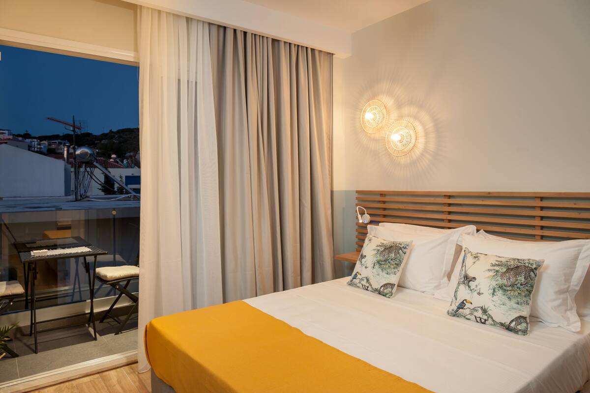 A hotel room with a bed, a desk, and a view of the outside.