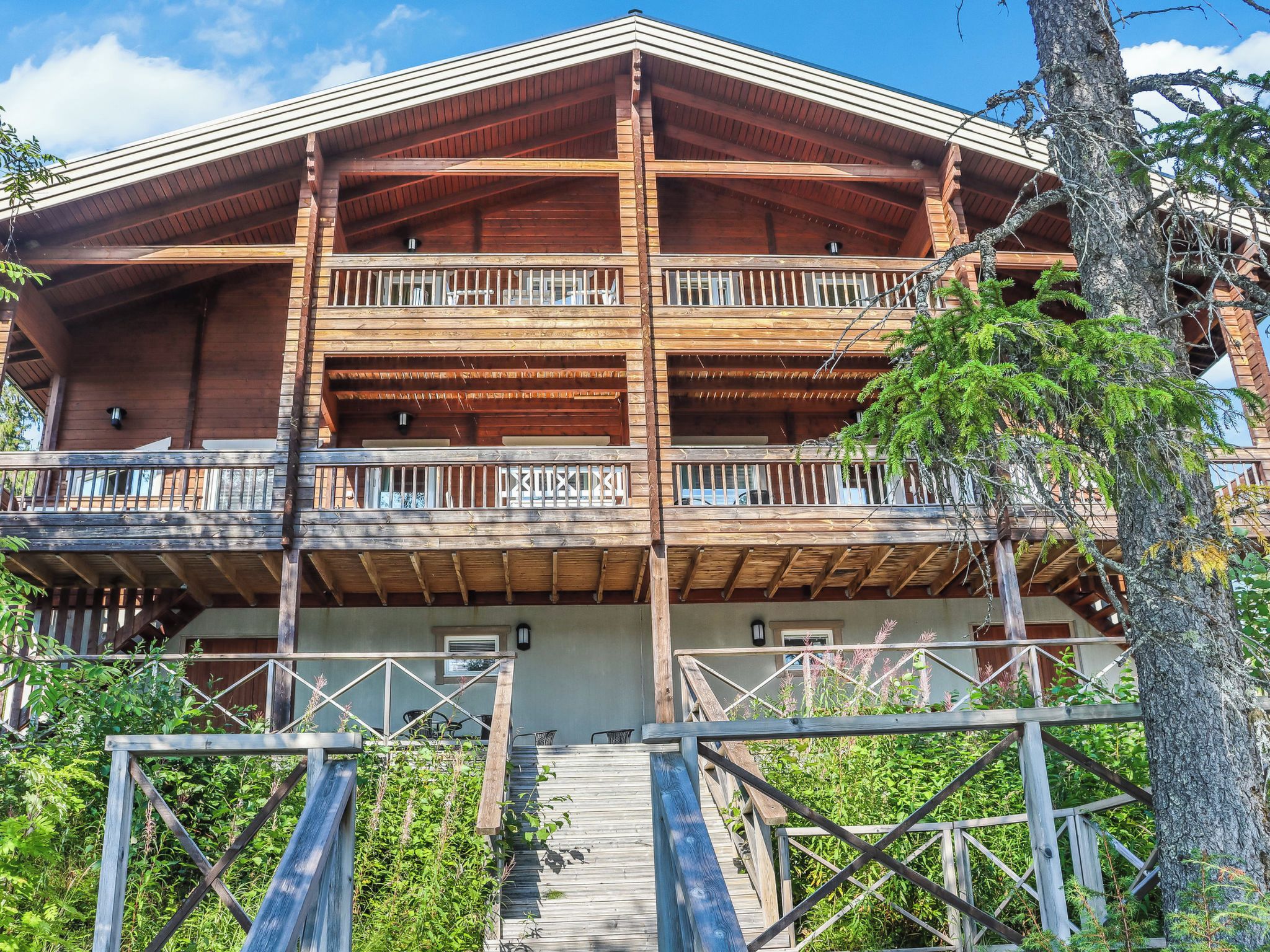 A multi-story wooden building with balconies and a staircase leading to the entrance.
