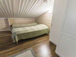 A small, cozy room with a sloped ceiling and wooden walls. There are two beds with green bedding. - Uulanlinna a, paritalo by Interhome (Hyrynsalmi)