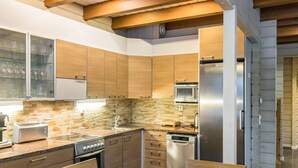 A modern kitchen with wooden cabinets, a granite countertop, stainless steel appliances, and a dining area with a wooden table and chairs. - Uulanlinna a, paritalo by Interhome (Hyrynsalmi)