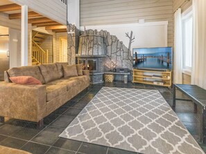 A cozy living room with a fireplace, a sofa, a TV, and a patterned rug. - Uulanlinna a, paritalo by Interhome (Hyrynsalmi)
