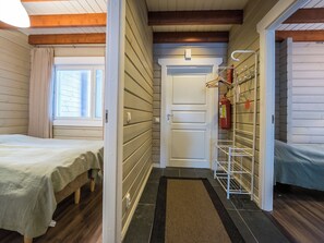 A room with a bed, a window with blinds, a door, and a fire extinguisher mounted on the wall. - Uulanlinna a, paritalo by Interhome (Hyrynsalmi)