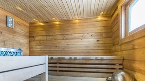 A sauna room with wooden walls, a bench, a small table, and a window. - Uulanlinna a, paritalo by Interhome (Hyrynsalmi)