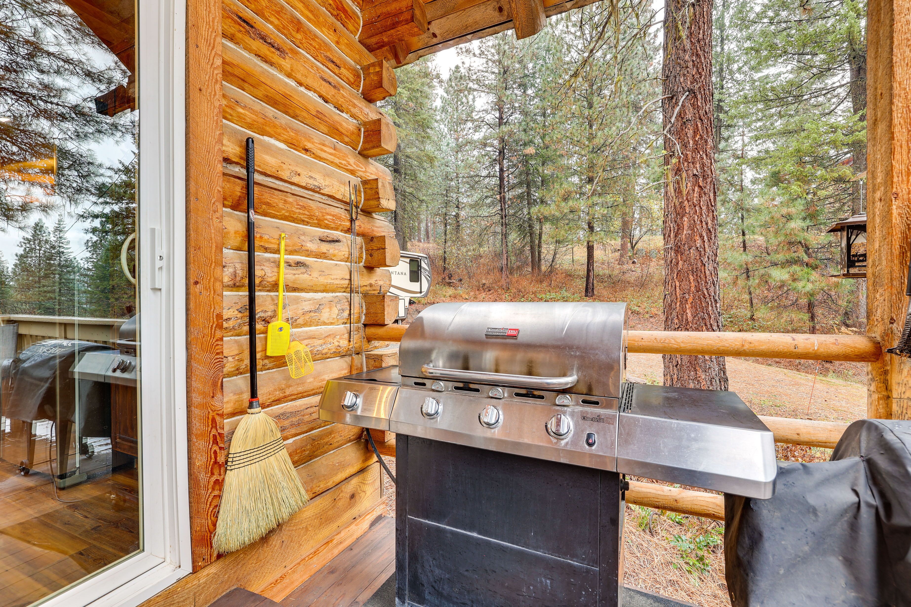A wooden cabin with a built-in grill and a view of the forest.