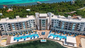 Een resort met meerdere zwembaden, een groot centraal zwembad en uitzicht op de oceaan.