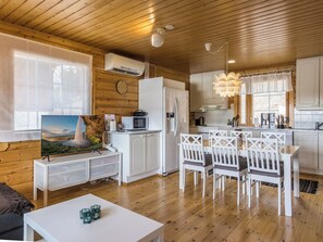 A modern kitchen with white cabinets, a microwave, and a refrigerator. There is a dining area with white chairs and a table.