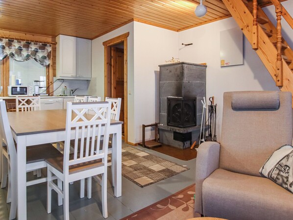A cozy living area with a fireplace, a dining table with chairs, and a sofa.