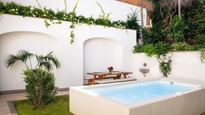 A rectangular swimming pool with a wooden table and chairs, surrounded by a white wall and greenery. - Luxury Apartment with Garden and Pool (Sant'Agnello)