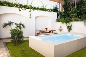 A rectangular swimming pool with a wooden table and chairs, surrounded by a white wall and greenery. - Luxury Apartment with Garden and Pool (Sant'Agnello)