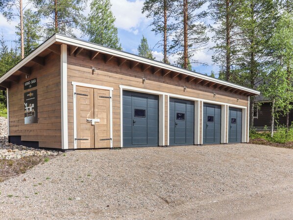 Rakennuksessa on puinen julkisivu, sorapäällysteinen ajotie ja kyltti, jossa lukee: ”AURINNO-SAAGA I-8”.
