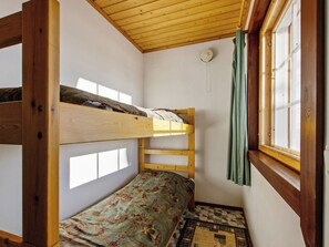 Ein kleiner, kompakter Raum mit einem Etagenbett, einem Fenster mit Vorhängen und einem gemusterten Boden.