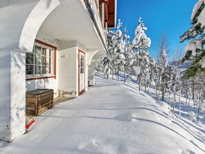 Un sentier enneigé mène à un bâtiment doté d’une porte et de fenêtres en bois.