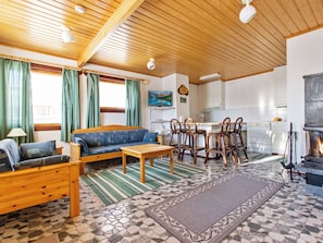 Una sala de estar acogedora con sofá, mesa de centro y sillas, una cocina con estufa, y un comedor con mesa y sillas.