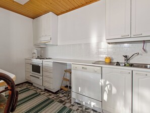 Une cuisine de taille réduite avec des meubles blancs, une cuisinière, un four et un lave-vaisselle.