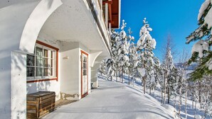 A snow-covered pathway leading to a building with a wooden bench and a door. - Alppikylä 13b by Interhome (Hyrynsalmi)
