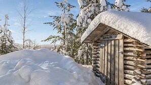 A wooden cabin with a snow-covered roof and a sign reading "AURALPPI". - Aurinkoalppi 10a by Interhome (Hyrynsalmi)
