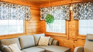 A cozy cabin interior with a sectional sofa, a single armchair, and a round wooden table. - Aurinkoalppi 10a by Interhome (Hyrynsalmi)