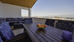 A wooden deck with a table, chairs, and a sofa. A bowl of fruit is on the table.