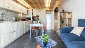 A modern kitchen with wooden cabinets, a dining area with a table and chairs, and a blue sofa in a living area. - Wonderful  villa for 6 guests with A/C, pool, WIFI, TV, patio and pets allowed (Deltebre)