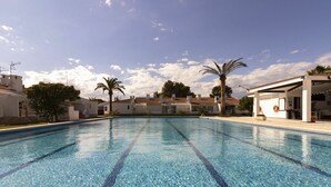 A swimming pool with clear water, surrounded by white buildings with tiled roofs and palm trees. - Wonderful  villa for 6 guests with A/C, pool, WIFI, TV, patio and pets allowed (Deltebre)