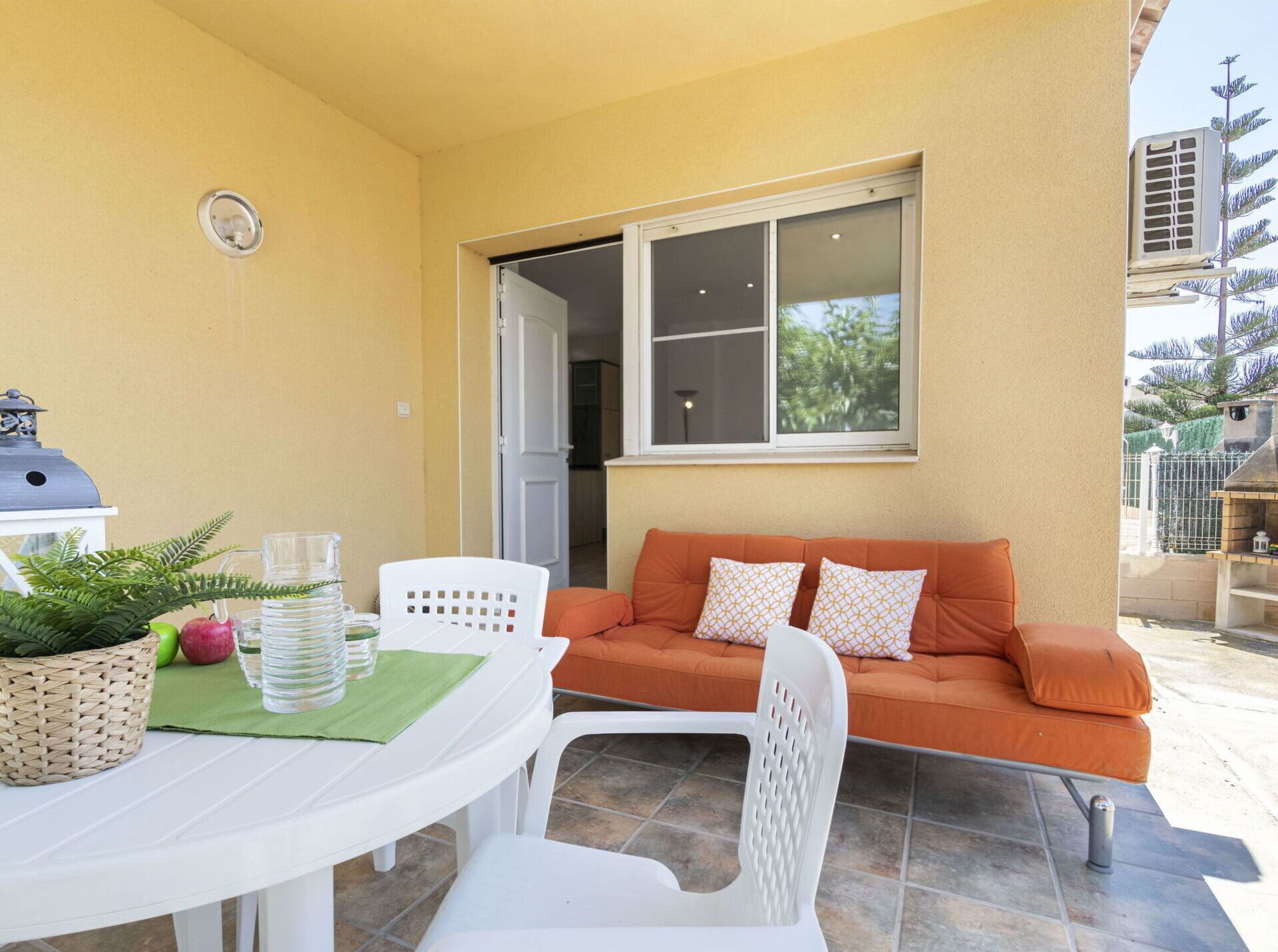 An outdoor patio area with a white table, chairs, a wicker basket, and a grill.