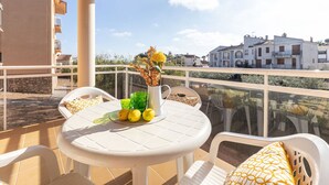 A balcony with a round table, chairs, a vase with flowers, and lemons. - Beautiful apartment for 4 guests with A/C, WIFI, TV and terrace (L'ampolla)