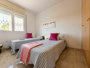 Een slaapkamer met twee bedden, een raam, een kunstwerk aan de muur en een deur.