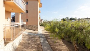 A multi-story building with balconies, a stone base, and a pathway leading to a garden area. - Beautiful apartment for 4 guests with A/C, WIFI, TV and terrace (L'ampolla)
